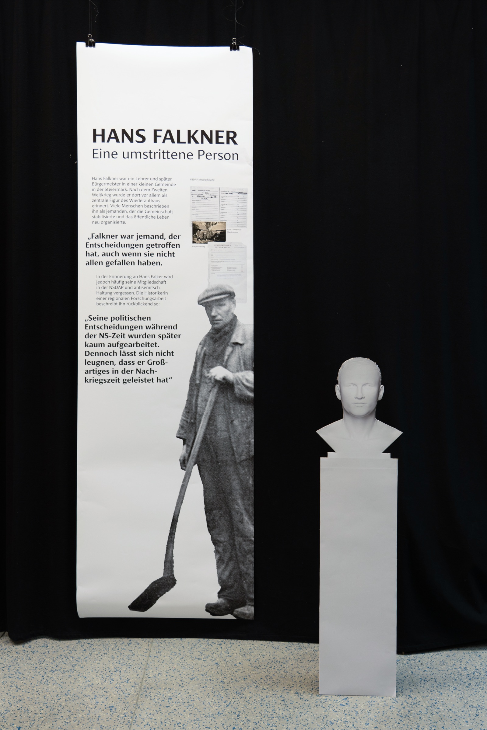 Ambivalent white-cube test version with a banner and a white bust